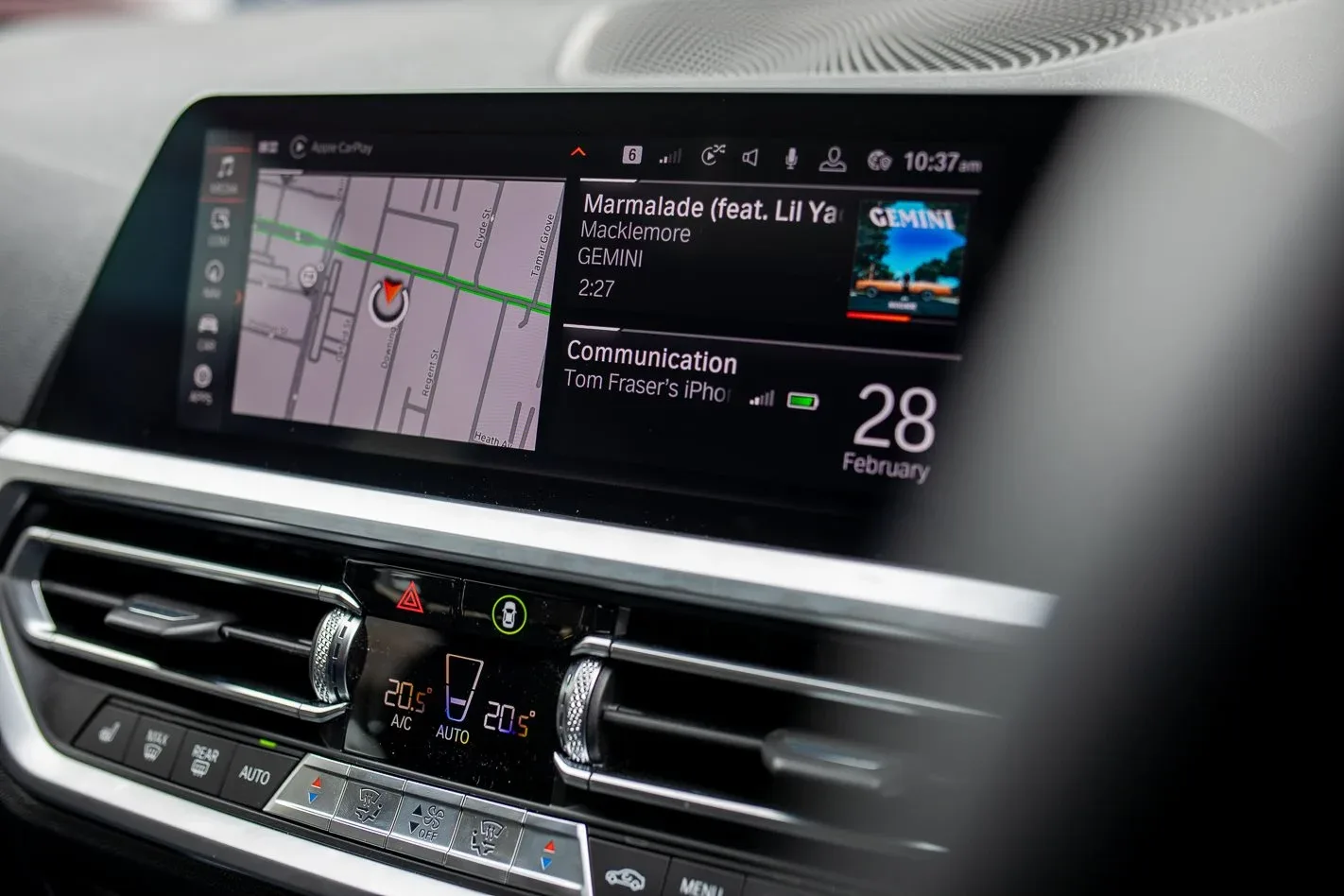 BMW iDrive infotainment system showing the navigation map alongside Apple CarPlay-connected music and communication widgets.