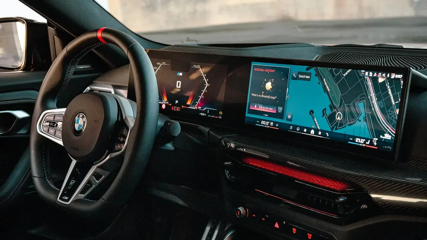 Modern BMW iDrive infotainment system with curved twin displays showing navigation and the BMW Personal Assistant.